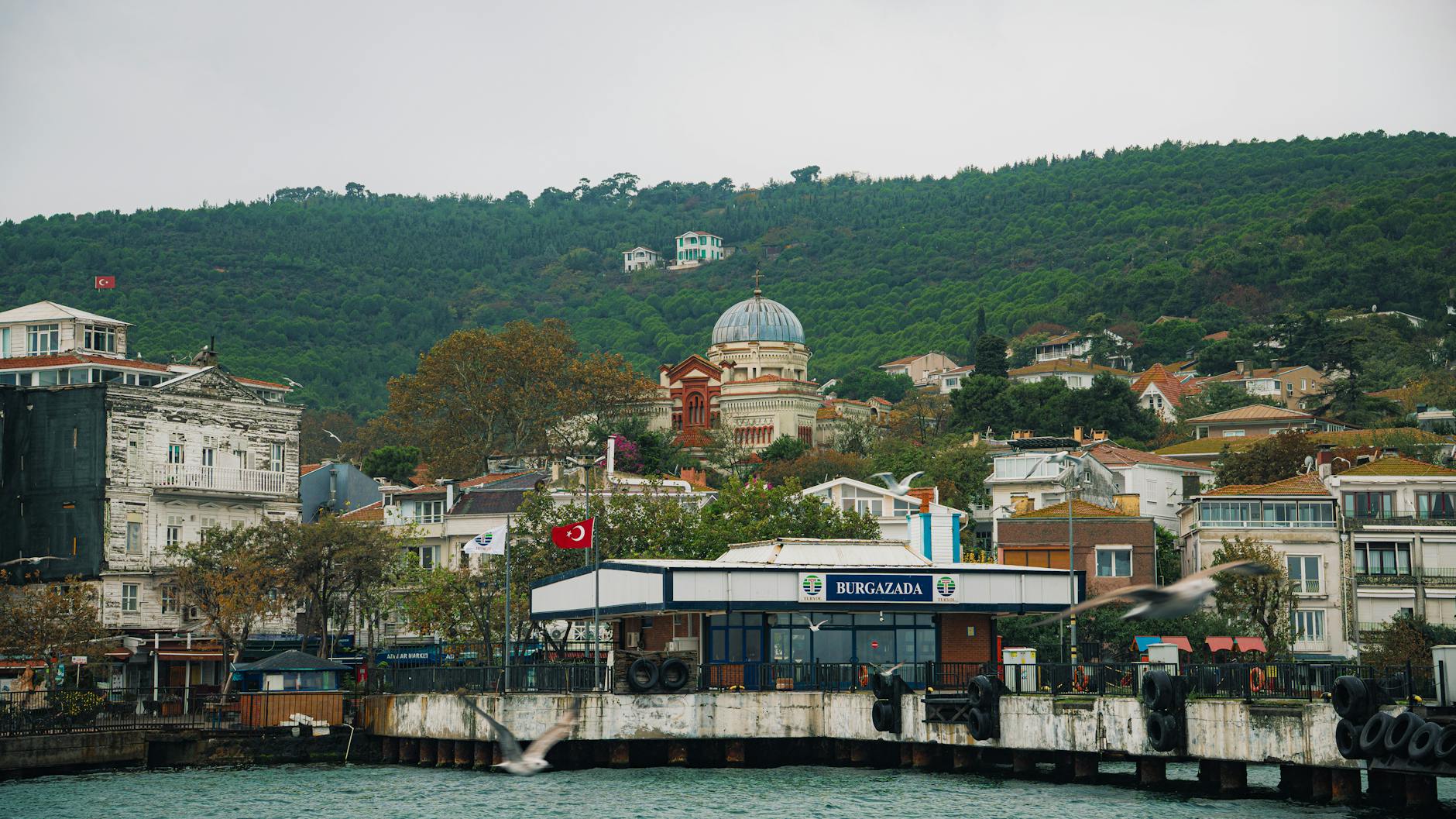 부르가자다 선착장 뒤로 보이는 평화로운 마을과 돔 지붕의 건물입니다.