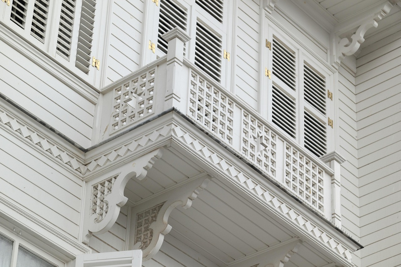 부유카다의 고풍스러운 분위기를 보여주는 전통적인 하얀색 목조 가옥의 정교한 발코니입니다.