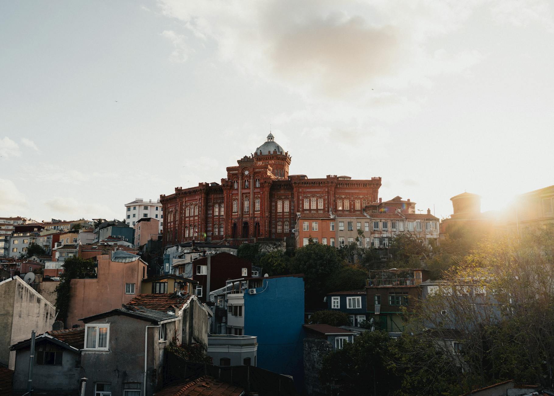 이스탄불 파나기아 발라리옷 교회 근처의 언덕 지대와 붉은 벽돌 건물 풍경, 해 질 녘 햇살이 비침