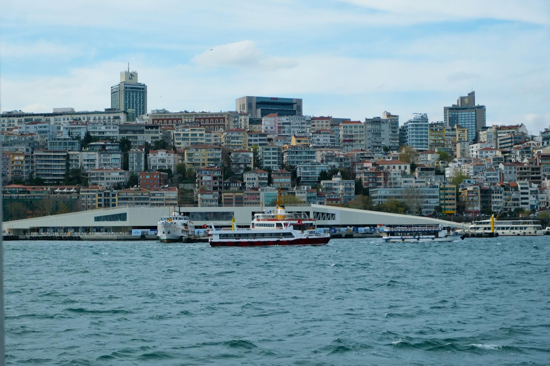 현대적인 건축물과 페리가 어우러진 이스탄불 카라쾨이 해안가의 평화로운 풍경입니다.