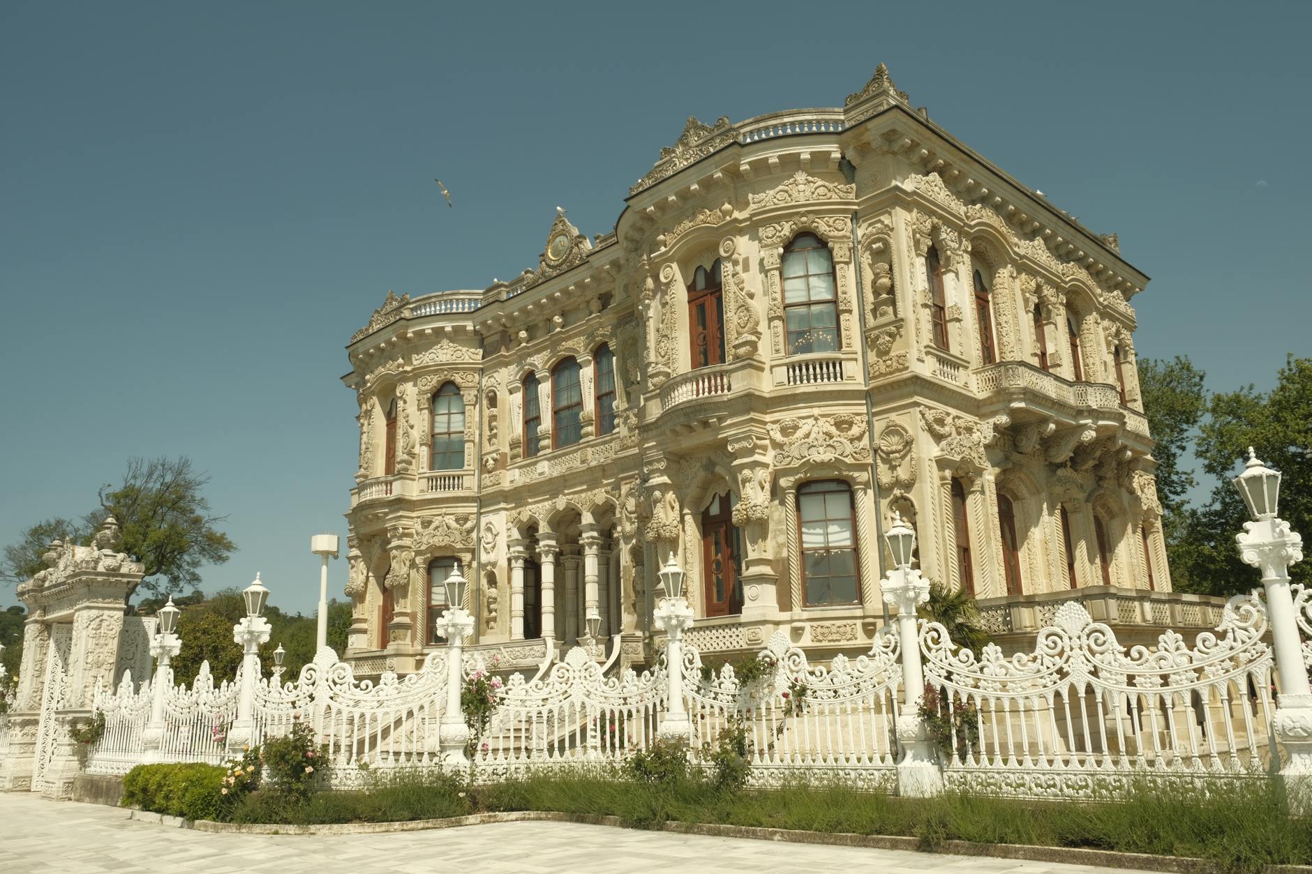 하얀색 울타리 너머로 보이는 퀴취크수 궁전의 정교하고 아름다운 석조 건물 모습입니다.