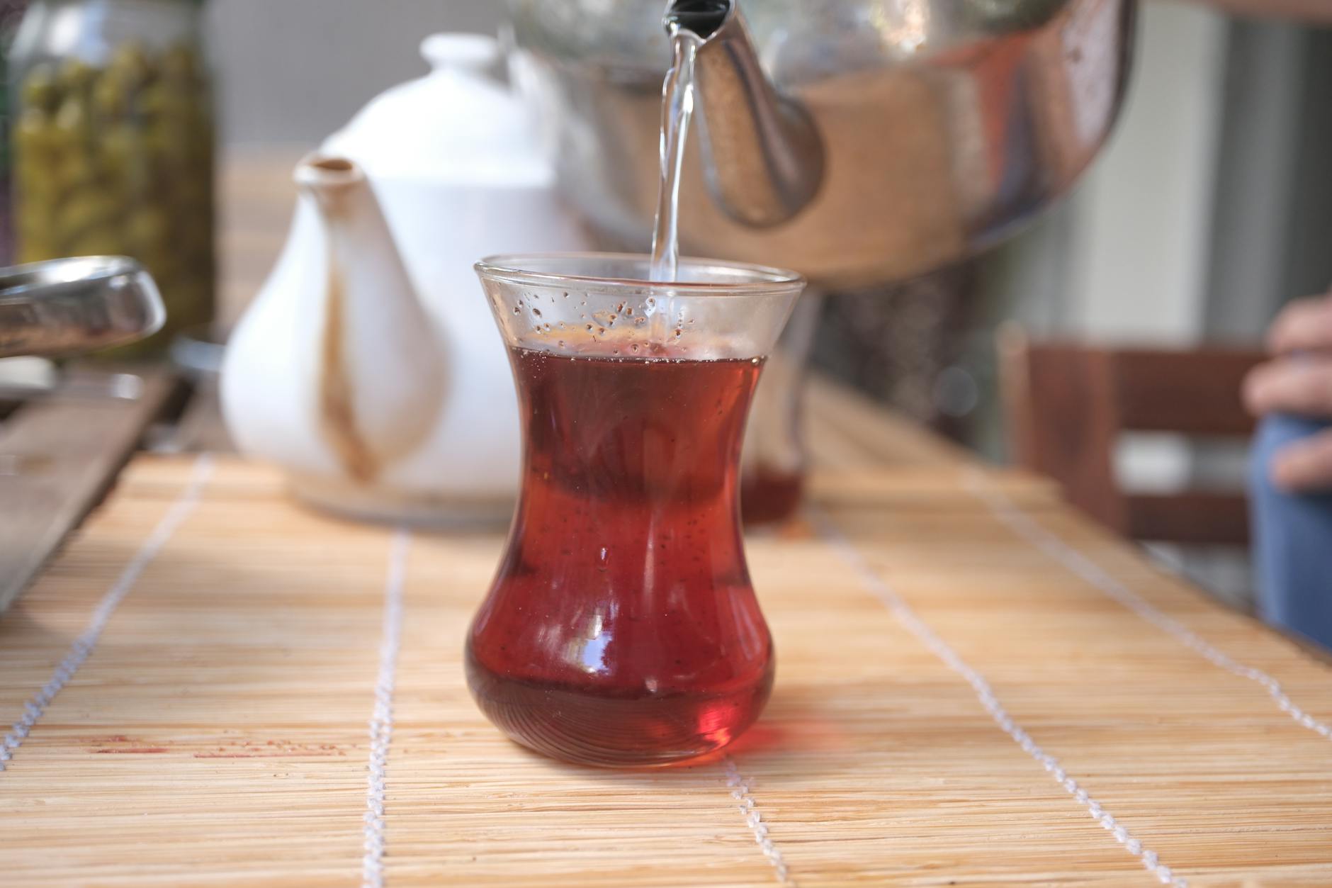 투명한 유리잔에 주전자로 신선하고 따뜻한 터키식 홍차를 정성스럽게 따르는 모습입니다.